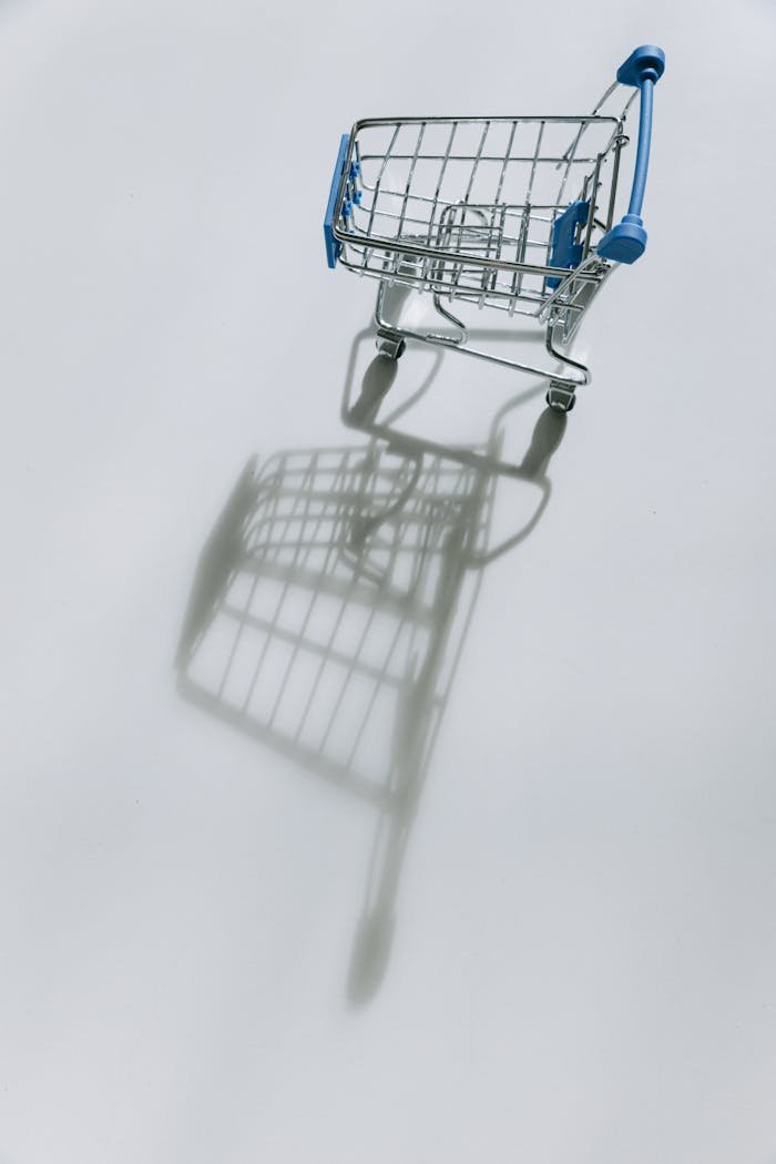 Empty shopping cart casting a shadow on white background.